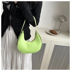 Close-up of a minimalist fluorescent green crescent underarm bag with matte leather texture