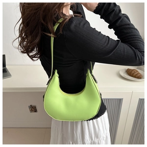 Detail view of the fluorescent green crescent shoulder bag worn on the shoulder