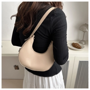 Detail of minimalist beige faux leather hobo bag worn on shoulder by a model