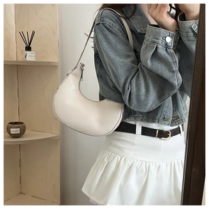 Detailed view of a white leather hobo bag with adjustable strap worn on the shoulder