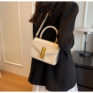 Modern cream leather handbag with elegant gold clasp shown on model in minimal interior