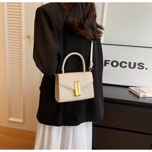 Rear view of model wearing cream square crossbody bag with gold lock and round handle