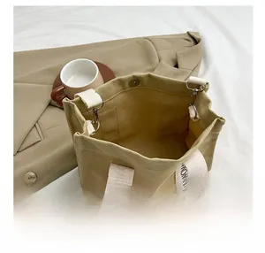 Dettagli della fibbia magnetica e dell'interno spazioso di questa borsa tote in tela kaki