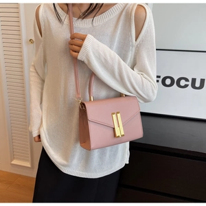 Detail of pink fashion handbag with golden buckle worn on shoulder by a model