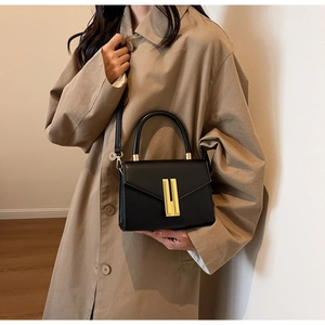 Close-up of black leather handbag featuring a polished gold rectangular metal clasp