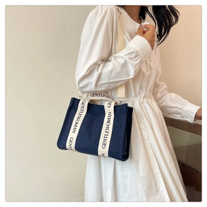 Dettaglio della borsa tote in tela blu navy con scritte GENTLEWOMAN sui manici