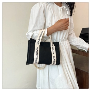 Dettaglio dei manici in fettuccia GENTLEWOMAN su una borsa tote in tela nera da donna