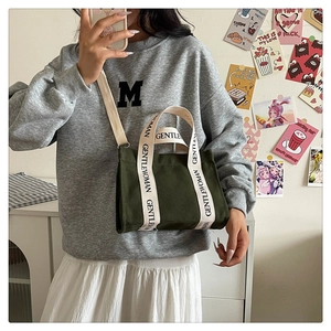 Dettaglio della borsa in tela verde scuro con manici GENTLEWOMAN in uno scatto lifestyle