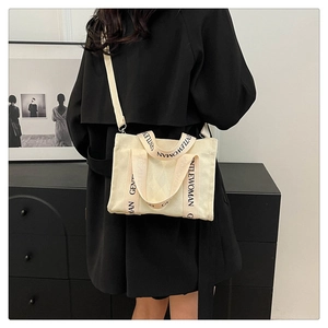 Dettaglio borsa tote in tela bianco sporco con tracolla GENTLEWOMAN su cappotto nero