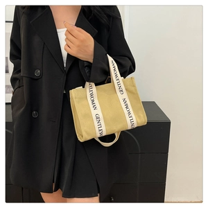 Borsa tote minimalista beige in tela con logo GENTLE WOMAN indossata con abito nero