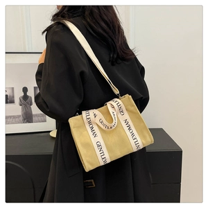 Vista laterale della borsa tote in tela kaki con tracolla e manici bianchi Gentlewoman