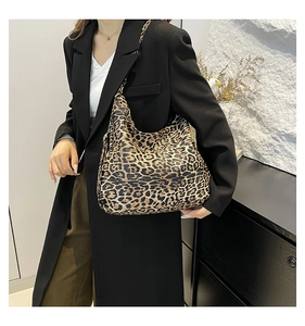 Close-up of leopard print canvas hobo bag worn by a model in a black blazer