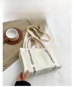Dettaglio borsa tote in tela crema con tracolla nera con logo Gentlewoman