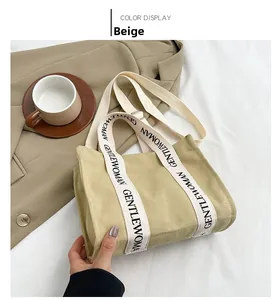 Dettaglio di una borsa tote in tela beige con cinghie stampate su sfondo in tessuto bianco