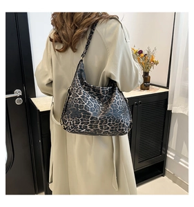 Leopard print hobo tote bag shown worn over the shoulder by a model in a beige trench coat