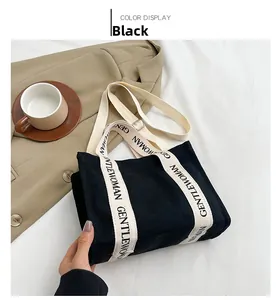 Dettaglio della borsa tote in tela nera con tracolla a lettere bianche e design elegante