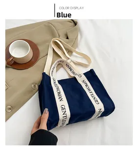 Dettaglio della borsa tote blu con scritta GENTLEWOMAN stampata sui manici in tela