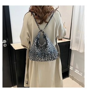 Detail of adjustable metal ring buckle on leopard print tote bag worn with a beige coat