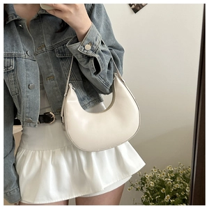 Minimalist cream leather half-moon baguette bag with adjustable strap and metal hardware