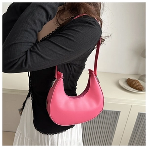 Chic pink crescent shoulder bag for women shown from a side view in a minimal setting