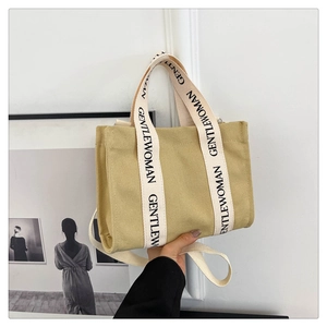 Borsa tote in tela beige con tracolla con scritta Gentlewoman per mano e spalla