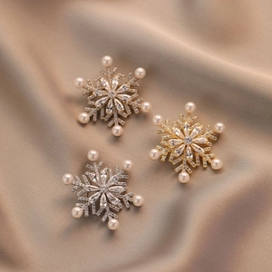 Elegant rotating snowflake brooches with crystals and pearls on champagne satin fabric