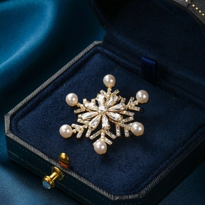 Golden snowflake brooch with zircons and pearls in a luxury blue velvet jewelry box