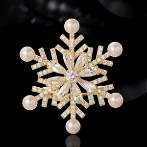 Rotating snowflake brooch with gold base, white pearls and sparkling crystal stones