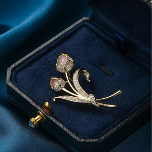 Elegante broche tulipán de oro con gemas rosas y cristales sobre terciopelo azul