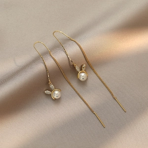 Elegant gold rabbit tassel earrings with pearls and crystals on silk background