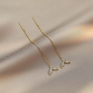 Elegant gold fishtail tassel earrings with cubic zirconia on champagne silk backdrop