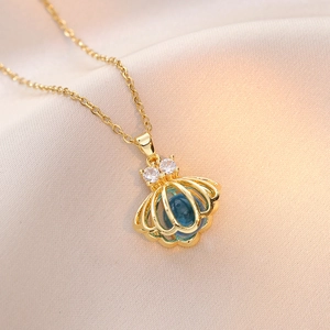 Collier doré avec pendentif coquillage, perle bleue et zircon sur fond en soie