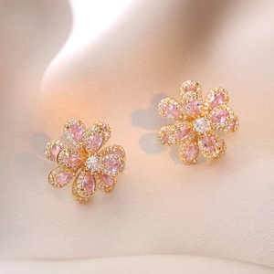 Boucles d'oreilles fleur en zircon rose avec plaqué or sur fond de soie couleur champagne