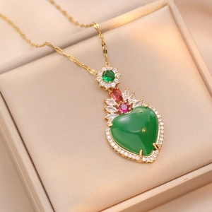 Detail of a gold heart necklace with a large green gemstone in a luxury silk jewelry box