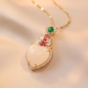 Detail of heart pendant with white stone and emerald top on champagne silk fabric