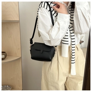 Side view of a vintage black matte crossbody bag with adjustable strap and gold hardware