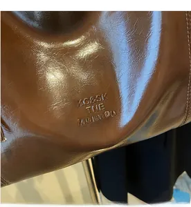 Detailed view of caramel brown oil wax leather tote with embossed logo and fine stitching