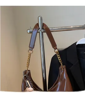 Detail of brown faux leather tote with golden chain strap and round decorative charm