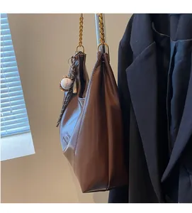 Brown leather tote with gold chain strap, side text and baseball charm detail