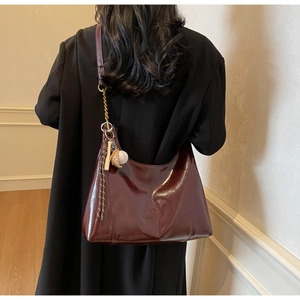 Detail of burgundy tote bag with glossy finish and baseball themed accessory