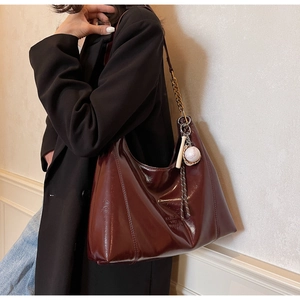 Detailed macro view of the glossy burgundy leather tote with a baseball bat charm