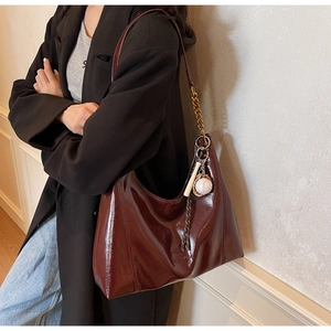 Detail of burgundy glossy hobo bag featuring baseball charm and embossed lettering