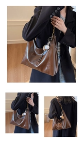Detail showing deep brown glossy tote bag with gold chain strap and baseball charm