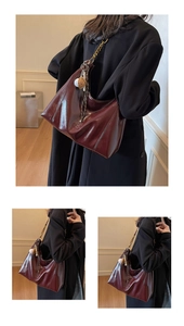 Detail of dark wine red leather tote bag with metal chain strap and plush pendant charm