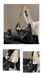 Detail of glossy black tote bag featuring vintage gold chain strap and baseball charms