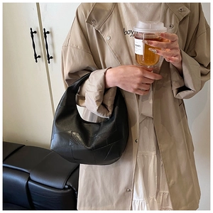 Detail of a black hobo bag with vintage patchwork texture paired with a stylish trench coat