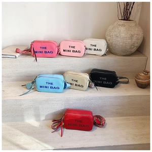 Multiple colors of grain leather crossbody bags displayed on minimalist stone steps
