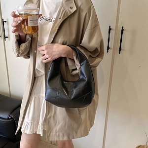 Chic black hobo bag with pebble leather texture shown in a lifestyle commuter fashion shot