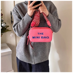 Pink pebbled leather mini camera bag featuring a wide geometric pattern strap and blue text