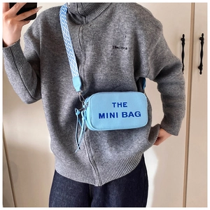 Detail of the light blue pebbled leather camera bag with a patterned wide shoulder strap